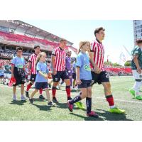 Manu Aparicio (middle) walks out onto the field at TD Place with Atlético Ottawa